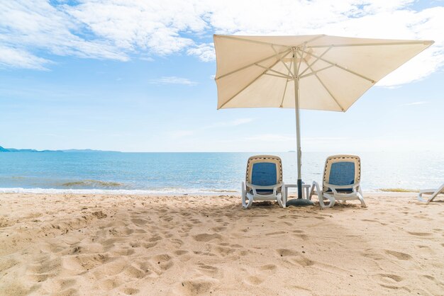 Al aire libre con paraguas y silla en la hermosa playa tropical y el mar