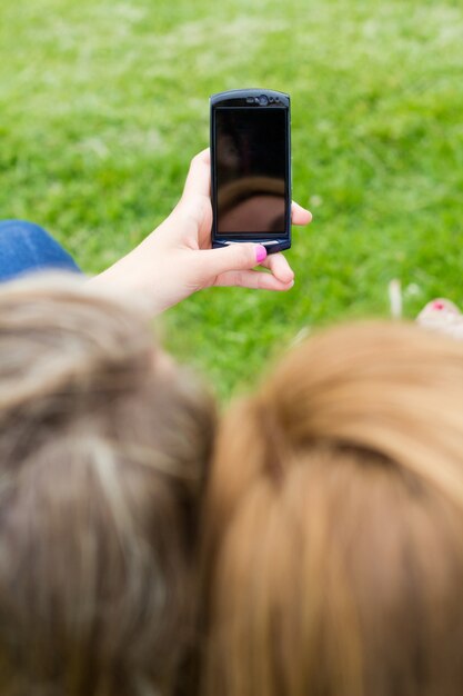 Al aire libre Retrato de dos hermosas mujeres jóvenes con móvil en el parque