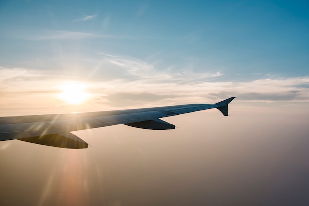 Ala de avión y puesta de sol en el cielo azul