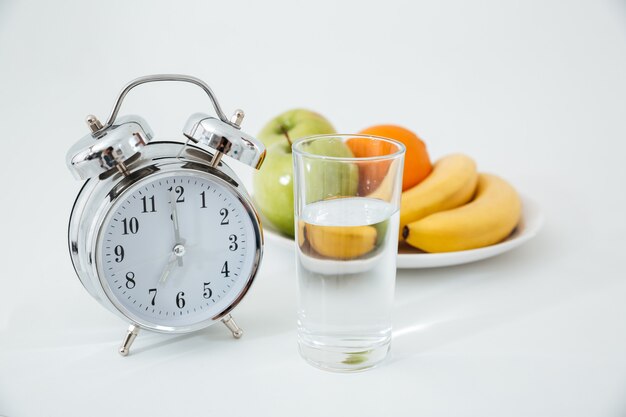 Alarma y vaso de agua cerca de frutas