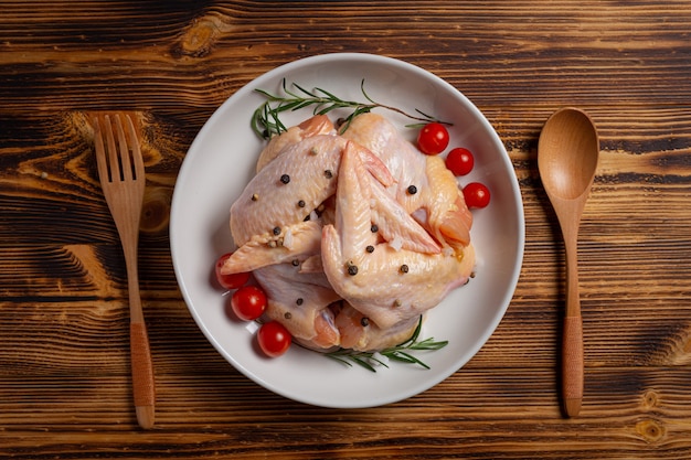 Alas de pollo crudo sobre la superficie de madera oscura.