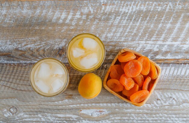 Albaricoques secos en un plato de madera con jugo, albaricoque fresco plano sobre una mesa de madera