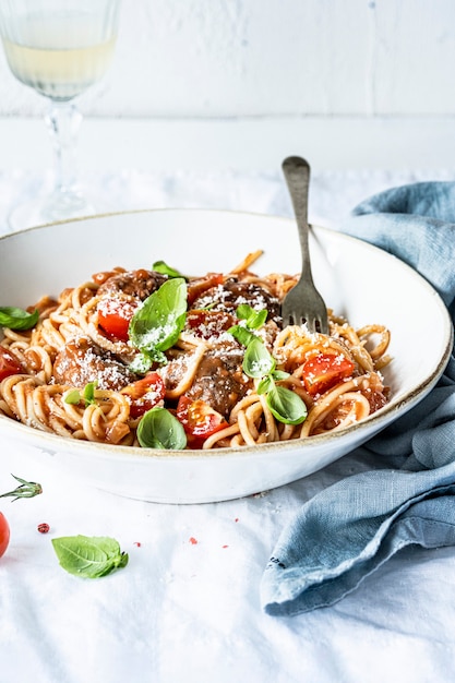 Albóndiga de espagueti con salsa de tomate marinara cubierta con parmesano y albahaca fotografía de alimentos