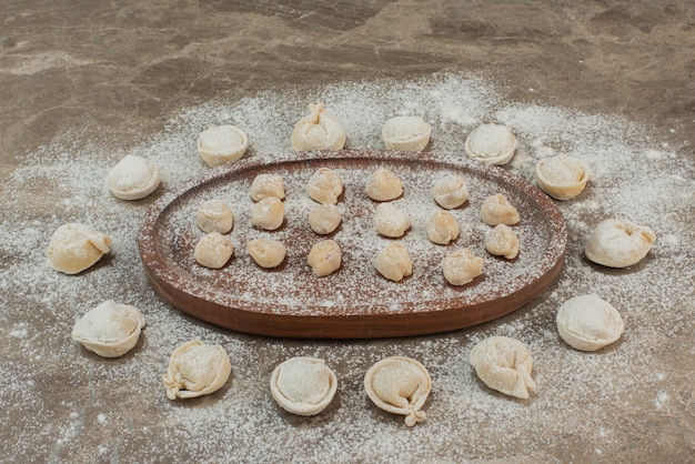 Foto gratuita albóndigas crudas sobre tabla de madera con harina.