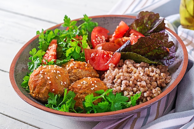 Albóndigas, ensalada de tomates y gachas de alforfón en mesa de madera blanca. Comida sana. Comida dietética Tazón de Buda.