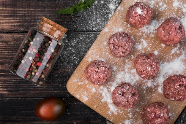 Albóndigas planas en tablero de madera con pimienta