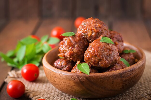 Albóndigas en salsa de tomate agridulce y albahaca en un tazón de madera