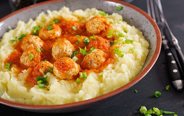 Albóndigas en salsa de tomate con puré de papas en un tazón.