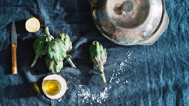 Alcachofas y aceite cerca de una cacerola