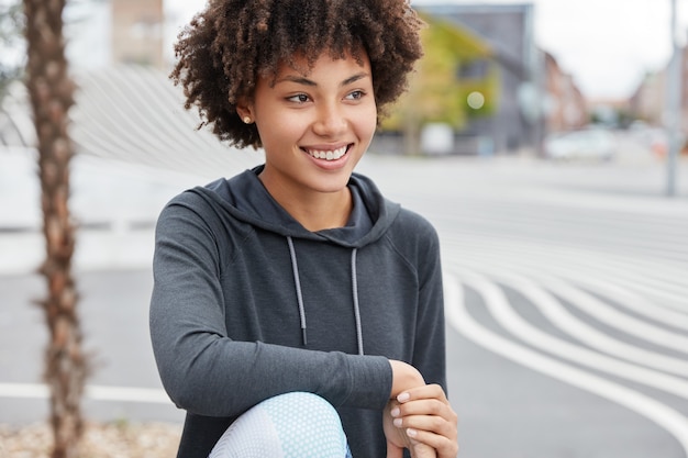 Alegre adolescente de piel oscura con una sonrisa encantadora, vestida de manera informal, disfruta del tiempo libre