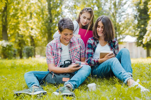 Alegre amigos con teléfono en el prado