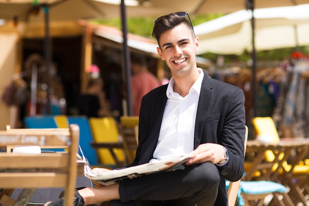 Foto gratuita alegre apuesto hombre de negocios descansando fuera de café