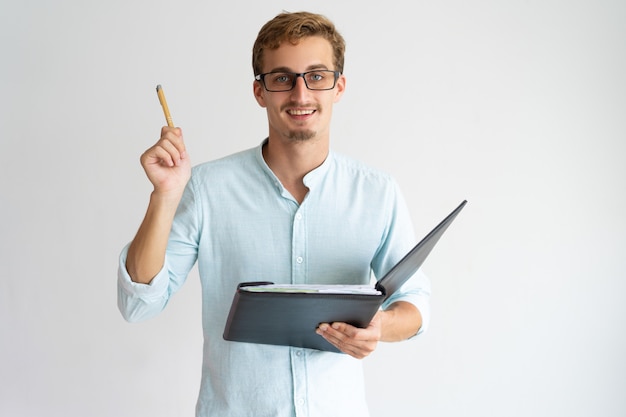 Alegre asesor financiero emprendedor con barba levantando la pluma mientras tiene idea