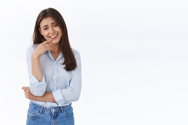 Alegre y atractiva joven empresaria, oficinista riendo y hablando con sus compañeros de trabajo, discuta un trato divertido reciente en el trabajo, ríe y tiene una agradable conversación amistosa, pared blanca