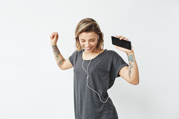 Alegre chica guapa joven sonriente escuchando música en auriculares bailando.