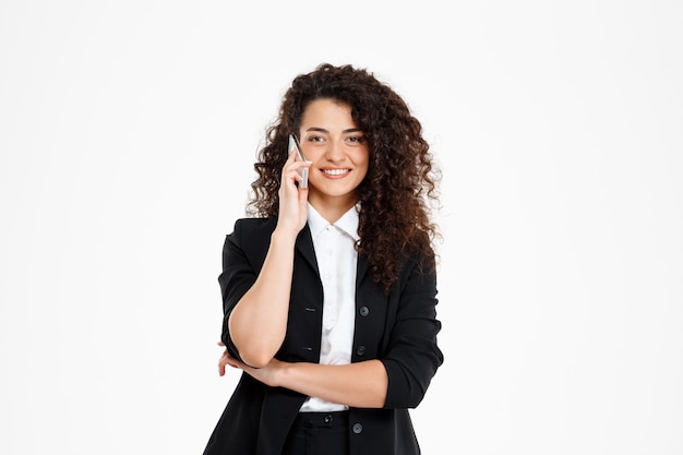 alegre chica de negocios rizada hablando por su teléfono