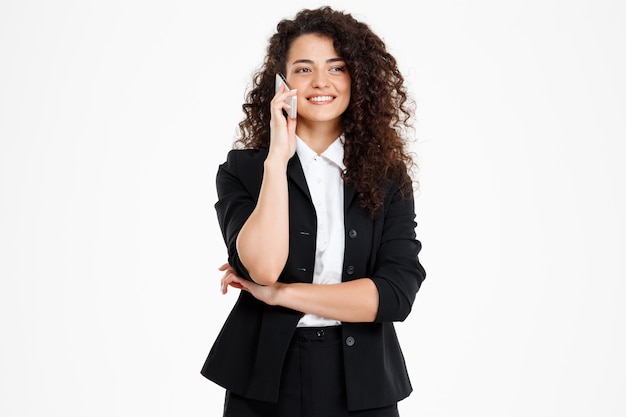 alegre chica de negocios rizada hablando por su teléfono