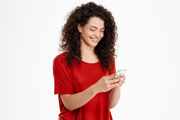 Foto gratuita alegre chica rizada chateando en su teléfono