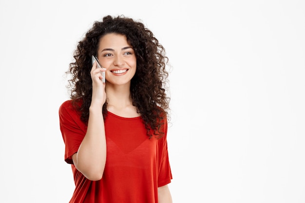 alegre chica rizada hablando por su teléfono