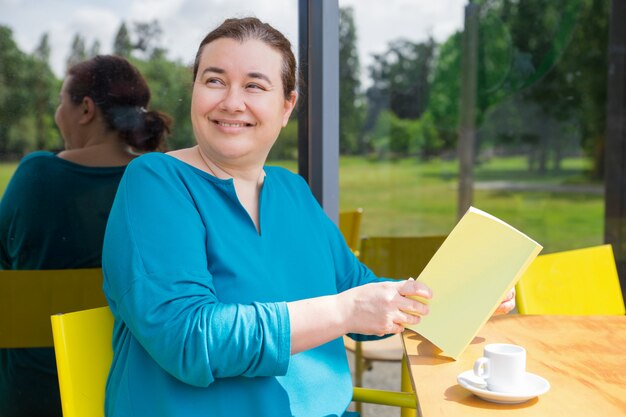 Alegre dama de mediana edad pasando su mañana en la cafetería.