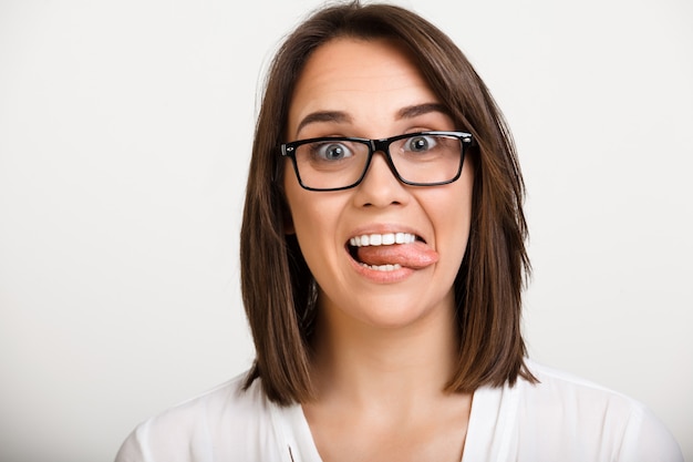 Alegre dama de oficina en gafas, muestra lengua feliz