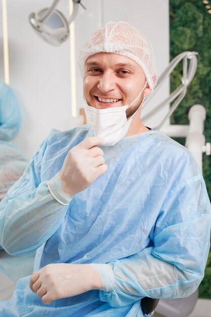 Alegre dentista masculino sentado en el consultorio dental