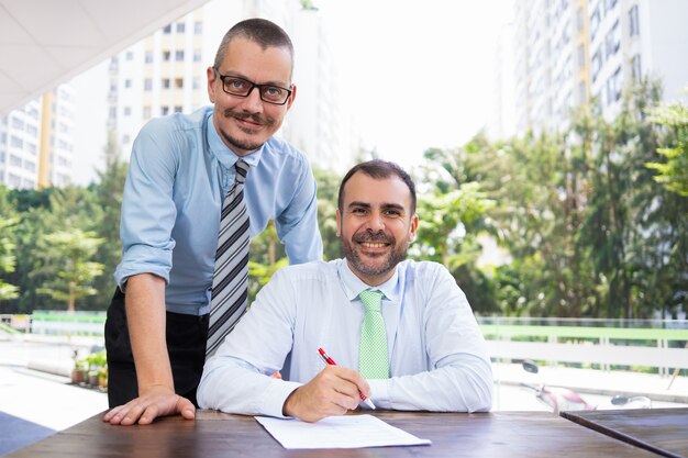 Alegre empresario hispano y asistente mirando a cámara