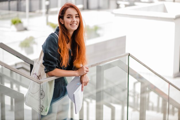 Alegre estudiante con docs mirando la cámara