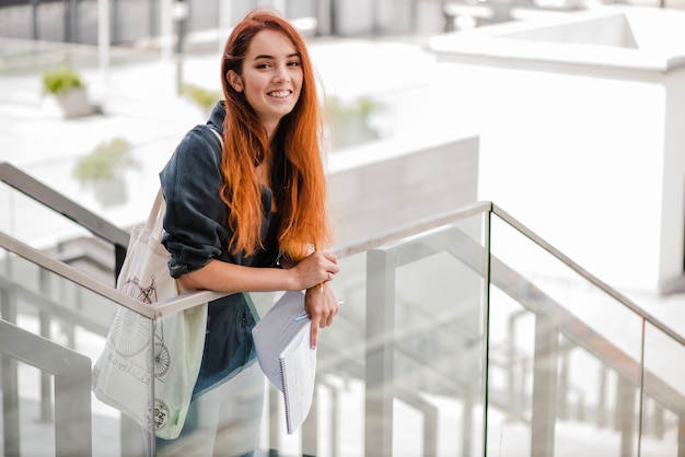 Alegre estudiante con docs mirando la cámara