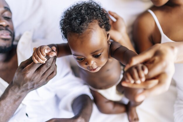 Alegre familia de afroamericanos con una madre, un padre y un bebé divirtiéndose juntos