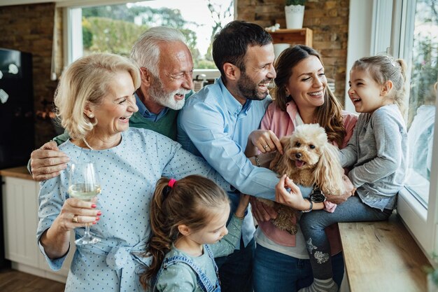 Alegre familia multigeneracional con un perro divirtiéndose mientras pasan tiempo juntos en casa.