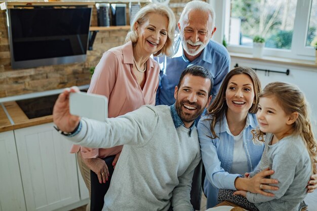 Alegre familia multigeneracional tomando selfie y divirtiéndose juntos en casa