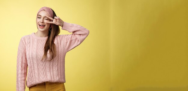 Alegre feliz glamour joven europea en suéter de punto rosa con diadema guiñando un ojo coqueto