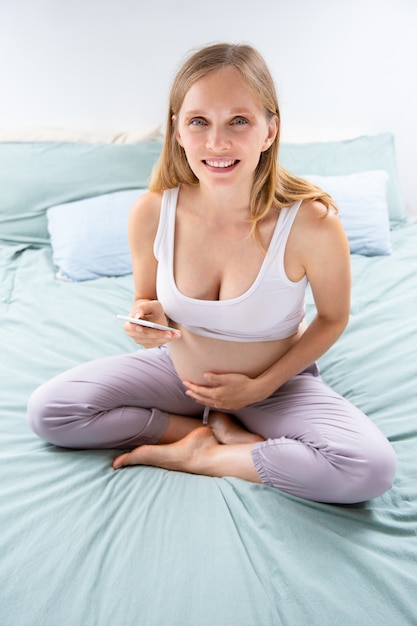 Alegre futura mamá usando la aplicación móvil en línea