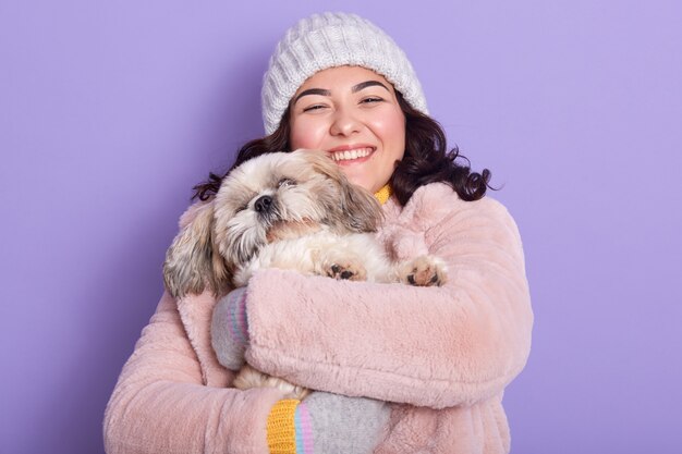 Alegre hermosa joven sosteniendo a su perro en ambas manos