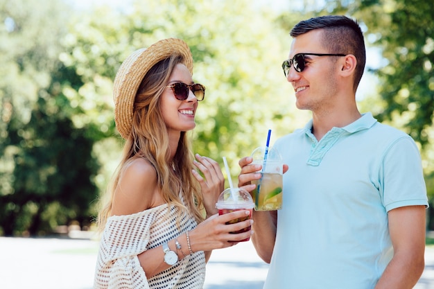 Alegre hermosa pareja divirtiéndose juntos, beber bebida fresca al aire libre