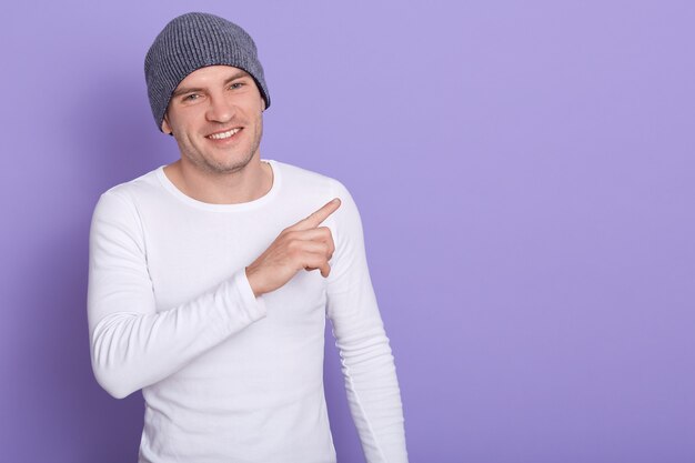 alegre hombre enérgico con agradable expresión facial, haciendo gestos con el dedo índice, sonriendo sinceramente, de buen humor. Copyspace para publicidad.