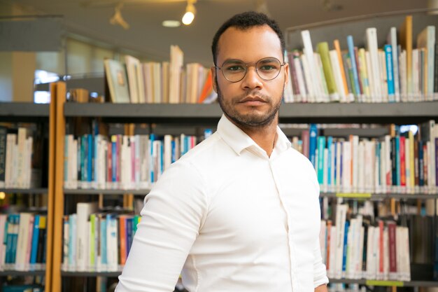 Alegre hombre negro posando en la biblioteca pública