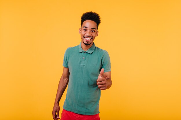 Alegre joven africano en traje verde sonriendo. Modelo masculino negro de buen humor riendo.