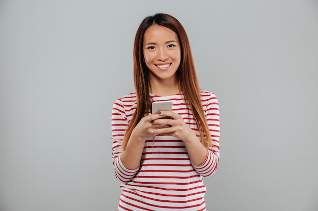 Alegre joven asiática hablando por teléfono