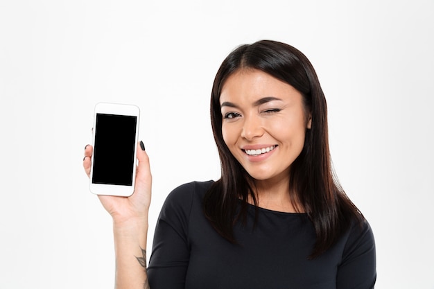 Alegre joven asiática mostrando la pantalla del teléfono móvil