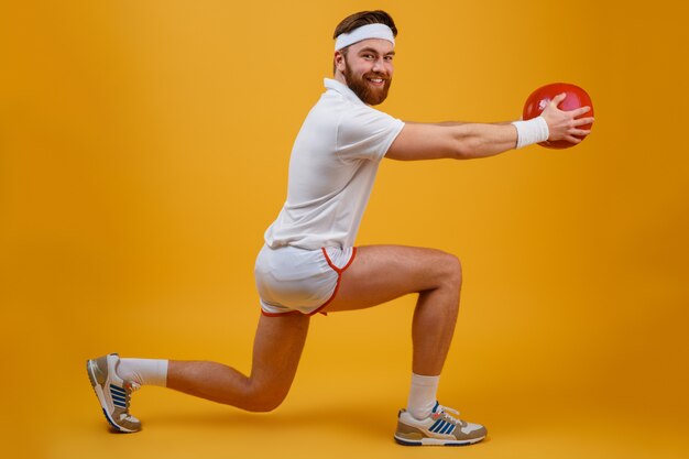 Alegre joven deportista hacer ejercicios deportivos sosteniendo la pelota.