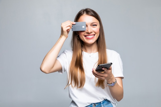 Alegre joven emocionada con teléfono móvil y tarjeta de crédito