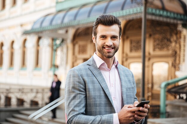 Alegre joven empresario caminando chateando por teléfono