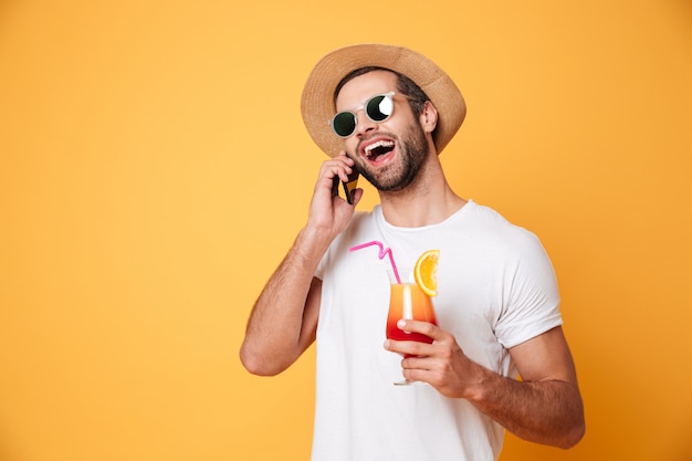 Foto gratuita alegre joven hablando por teléfono con cóctel