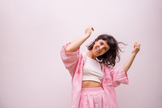 Alegre joven morena caucásica en camiseta y pantalones se mueve activamente posando sobre fondo blanco Gente emociones estilo de vida y concepto de moda