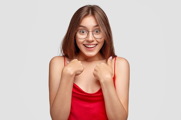 Alegre joven morena posando contra la pared blanca