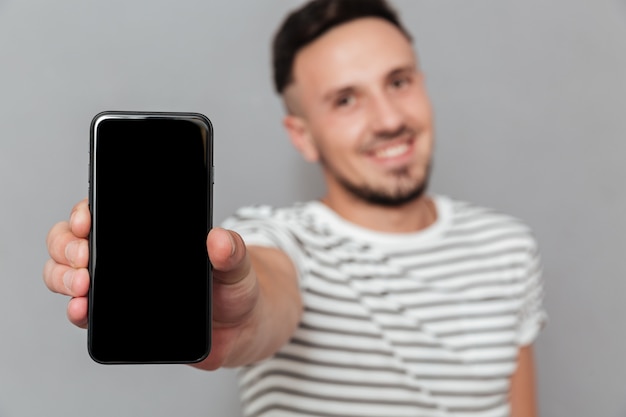 Alegre joven mostrando la pantalla del teléfono móvil