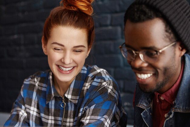 Alegre joven mujer caucásica de jengibre en camisa a cuadros sonriendo felizmente durante la fecha