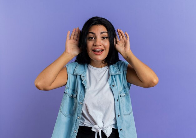 Alegre joven mujer caucásica tiene las manos cerca de la cabeza aislada sobre fondo púrpura con espacio de copia